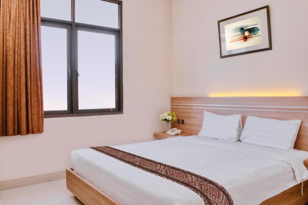 een slaapkamer met een bed en een raam bij Gapura Residence Airport Semarang by Sinergi in Semarang