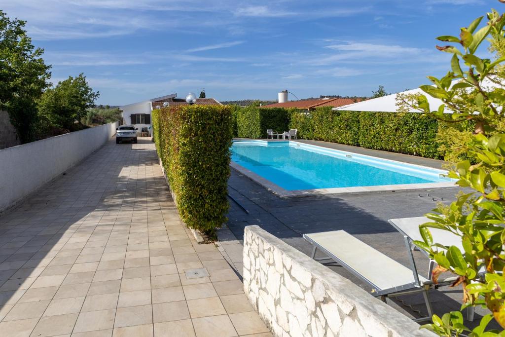 - une piscine avec une haie à côté d'une maison dans l'établissement Villa Giacomo con piscina, à Santa Maria Del Focallo