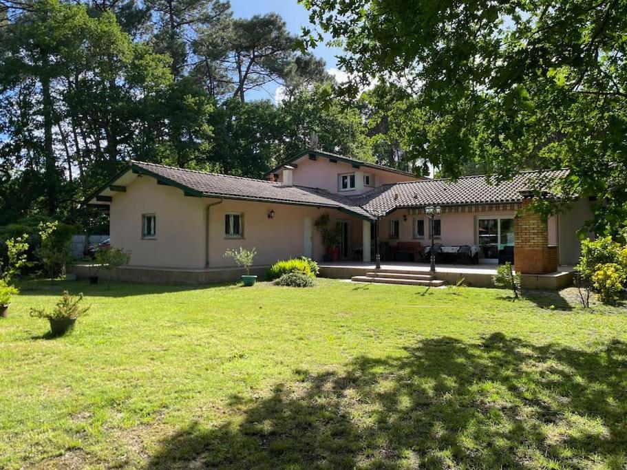 une maison avec une cour dotée d'une pelouse dans l'établissement Maison familiale dans un grand jardin arboré, à Gujan-Mestras