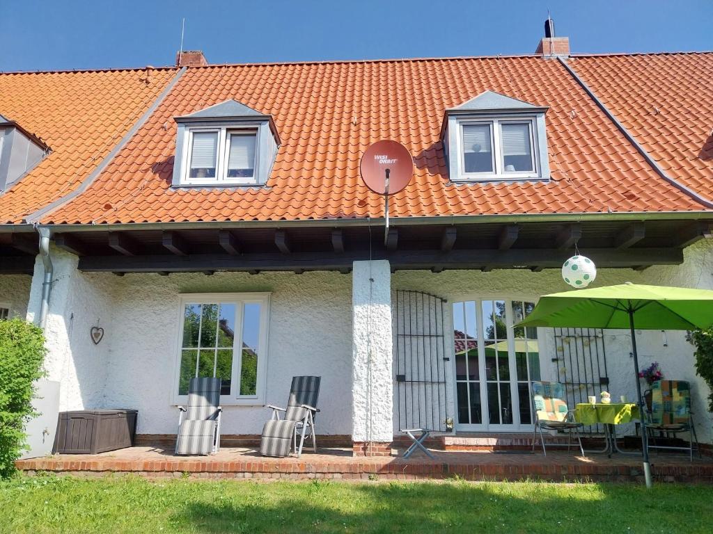 a house with an orange roof with chairs and an umbrella at Anni in Zingst