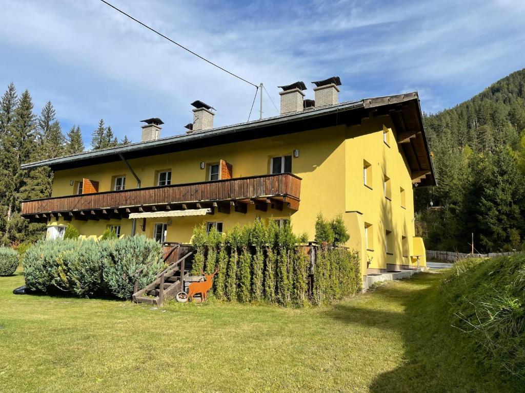 una gran casa amarilla con una valla delante en Ferienwohnung Collie en Nauders