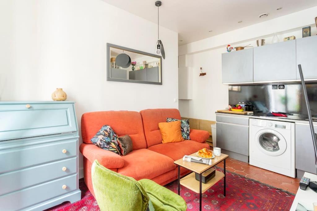 un salon avec un canapé orange et une cuisine dans l'établissement Charmant 2 pieces Parisien à 10 min de MONTMARTRE, à Paris