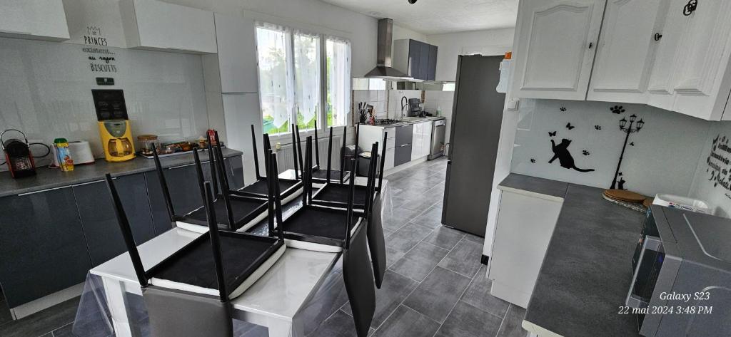 une cuisine avec des chaises noires et des placards blancs dans l'établissement Pavillon avec jardin clos au bord de l'Yonne, à Coulanges-sur-Yonne