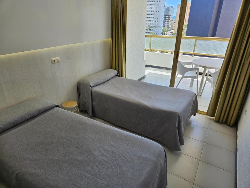 a hotel room with two beds and a balcony at Apartamentos Maria Victoria in Benidorm