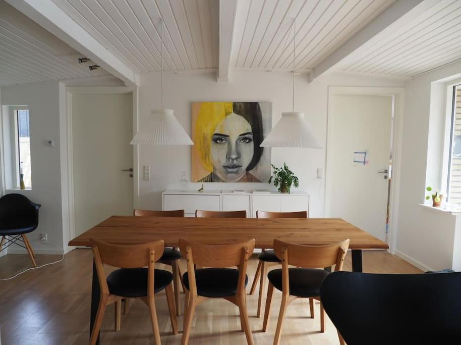 a dining room with a large wooden table and chairs at Bolig med sommerhusvibes, 80 meter fra badesø in Silkeborg