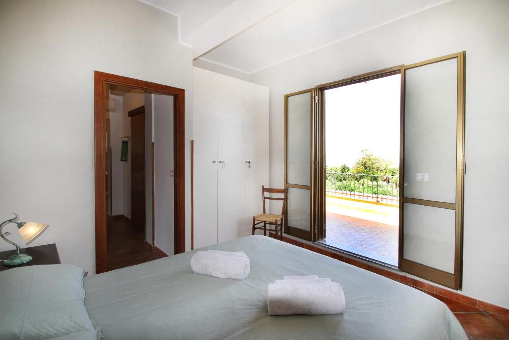 een slaapkamer met een bed en een groot raam bij Il giardino al mare di Anna in Caronia Marina