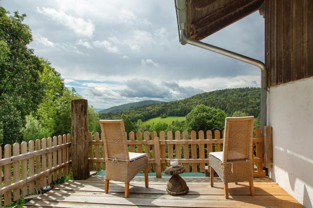 ein Teddybär auf einer Veranda mit zwei Stühlen in der Unterkunft Landhaus am Eselhof Daxstein in Schöllnach