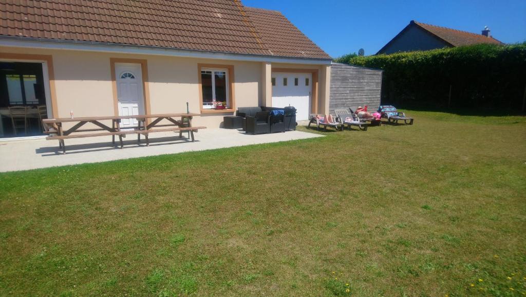 un groupe de bancs assis dans une cour à côté d'une maison dans l'établissement Hébergement Plage du Débarquement - 6/10 pers, à Sainte-Mère-Église