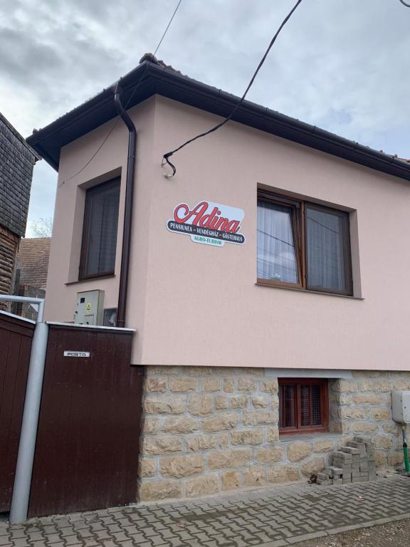 a building with a sign on the side of it at Adina Vendégház in Sîncraiu
