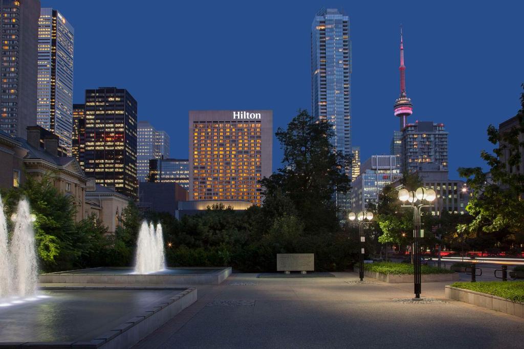 a fountain in a park with a city at night at Hilton Toronto in Toronto