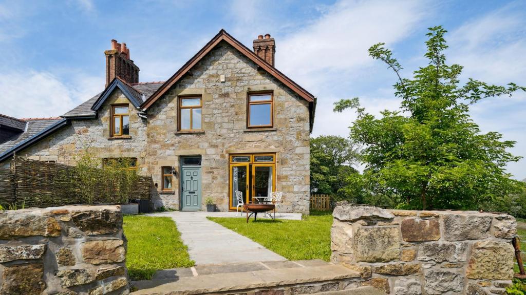 an old stone house with a stone wall at Tranquil countryside cottage for two in Wrexham