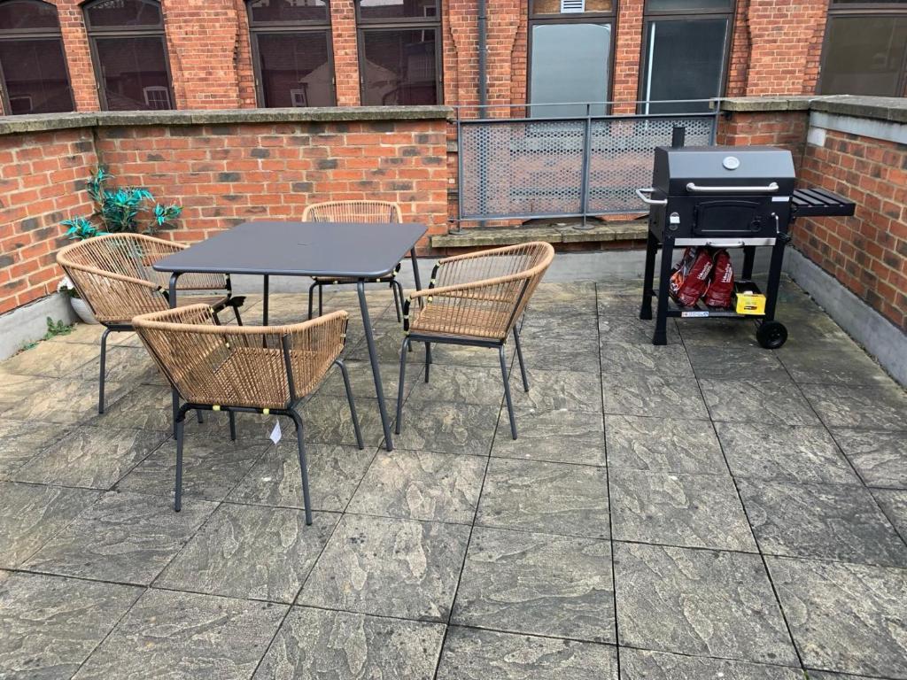 een patio met een grill, stoelen en een tafel bij Central Leeds townhouse with private roof garden Sleeps 4 in Leeds