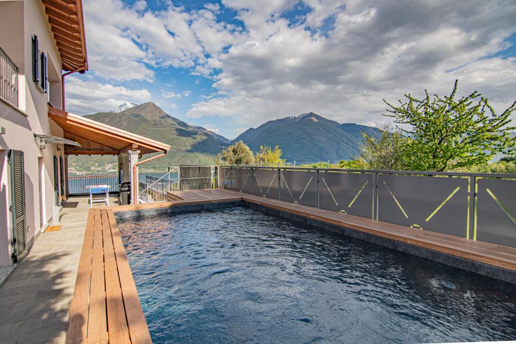 une piscine avec une terrasse et des montagnes en arrière-plan dans l'établissement VILLA DEI VENTI - BREVA by Curtiaffitti, à Pianello Del Lario
