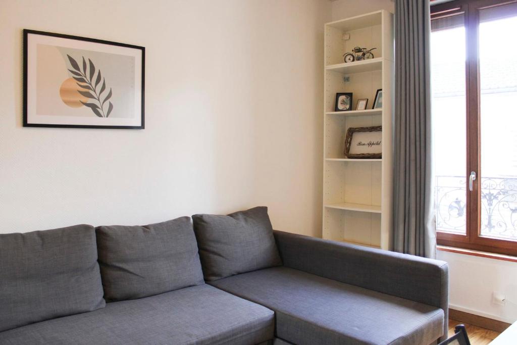 - un salon avec un canapé gris et une fenêtre dans l'établissement Charming studio near Paris, à Saint-Ouen