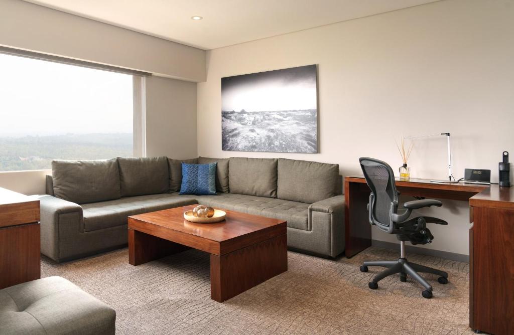 A suite-style living area combining a sectional sofa, coffee table and dedicated desk.