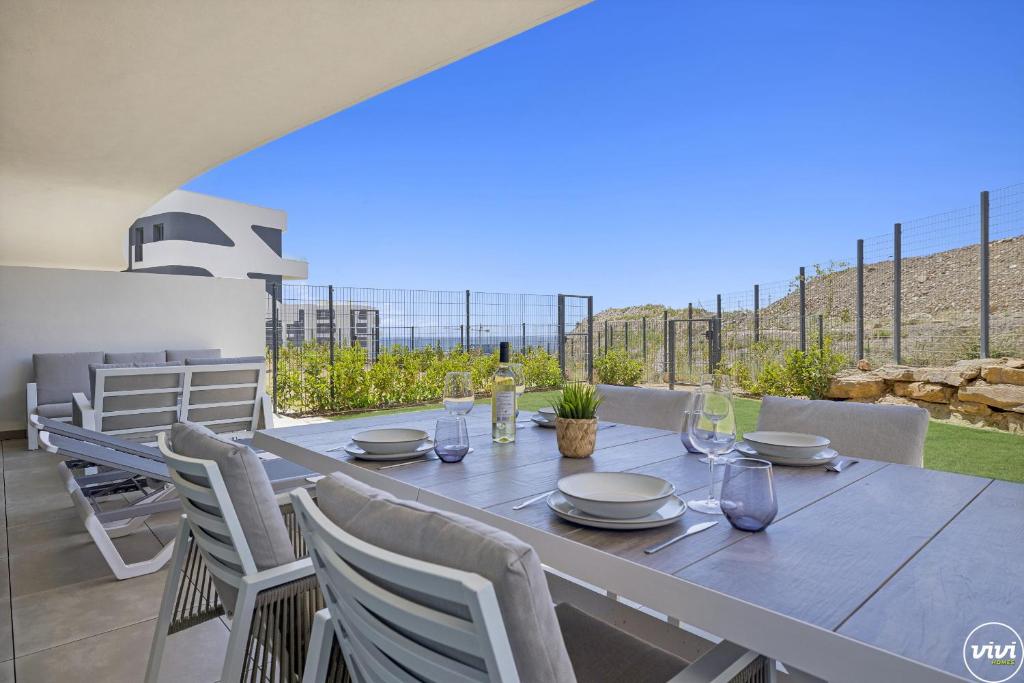 mesa de comedor con sillas blancas y vistas al océano en ViVi Homes - Levalin Wellness, Pool & Terrace, en Fuengirola