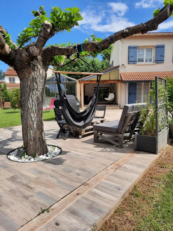 a patio with a hammock and a tree at Gîte ma vie là avec jacuzzi privatif in Saint-Julien-de-Cassagnas