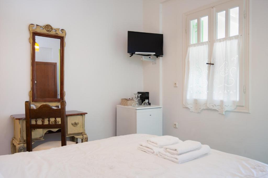 a white bedroom with a bed and a mirror at Villa Areto in Kamares