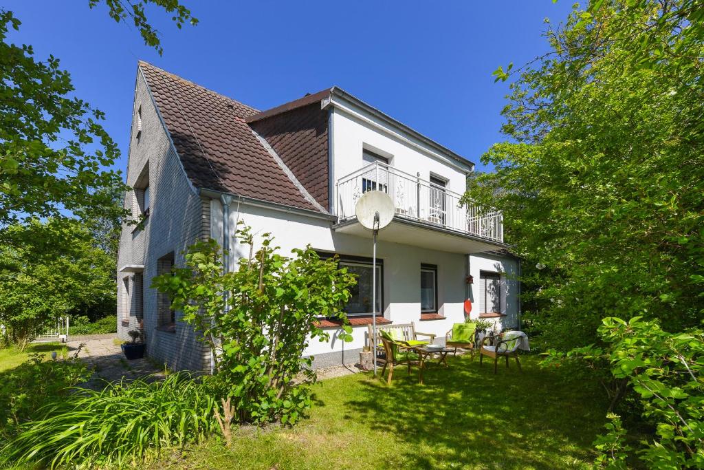 uma casa branca com uma varanda e um quintal em Ferienwohnung AnneHuus em Bensersiel