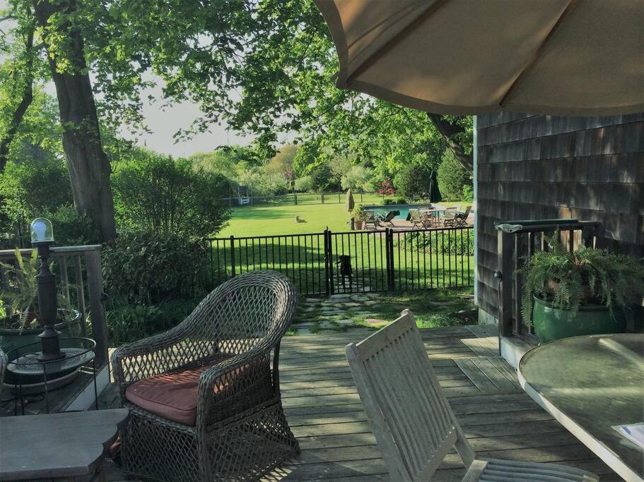 eine Terrasse mit zwei Stühlen und einem Sonnenschirm in der Unterkunft The Heritage August w LD full month in Bridgehampton