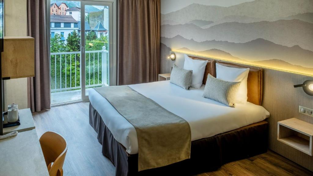 a hotel room with a large bed and a window at H&ocirc;tel La Solitude in Lourdes
