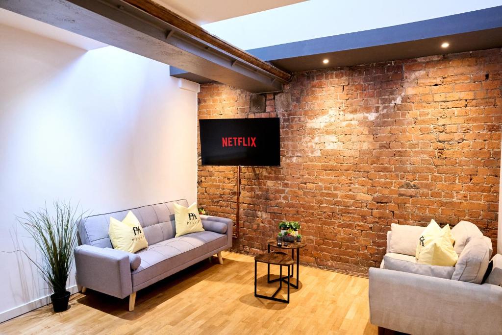 un soggiorno con 2 divani e un muro di mattoni di Pluxa Citronella -2 floors Home of football location with Workspace a Manchester