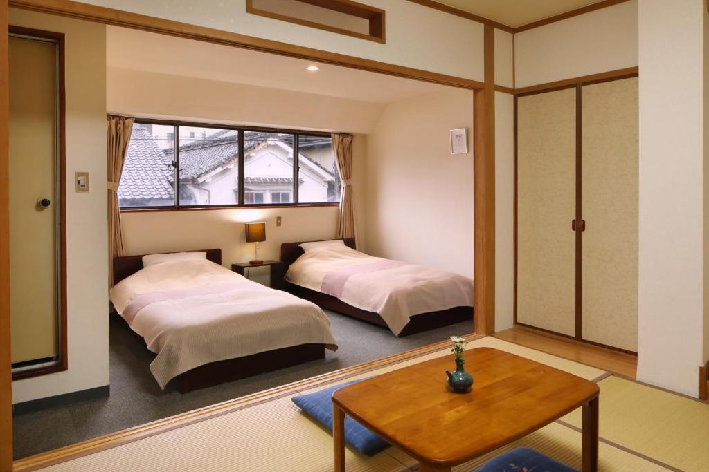 Cette chambre comprend 2 lits et une table. dans l'établissement Travel Inn Yoshitomi - Vacation STAY 37637v, à Taketa