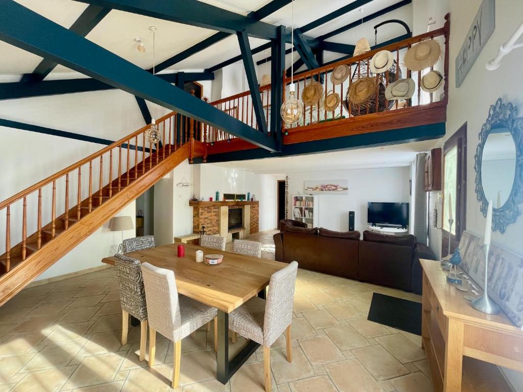 a dining room with a wooden table and a staircase at Maison à la campagne avec PISCINE et JACUZZI in Buanes