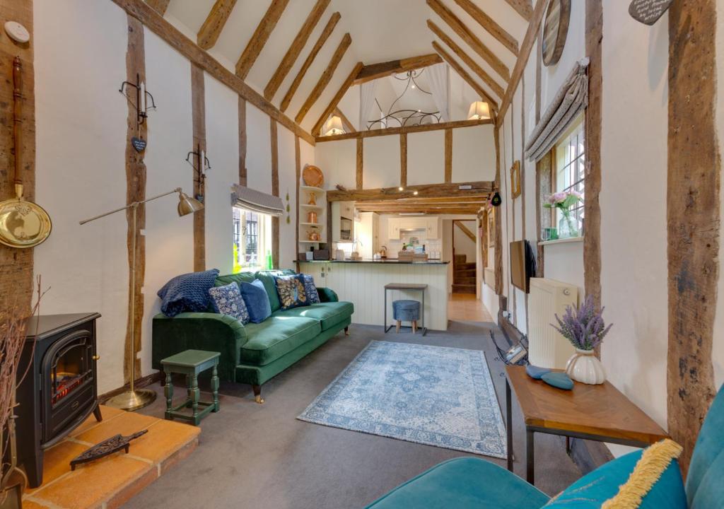 a living room with a green couch and a fireplace at Lady Cottage in Lavenham