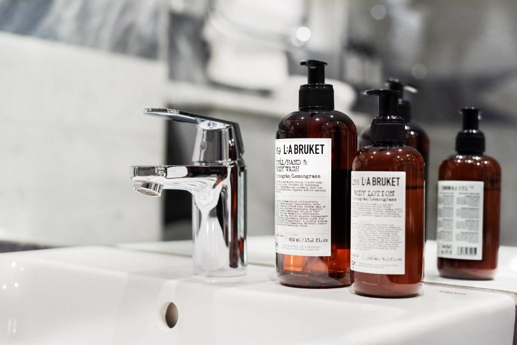 three bottles of soap sitting on a bathroom sink at Hotel Hasselbacken in Stockholm