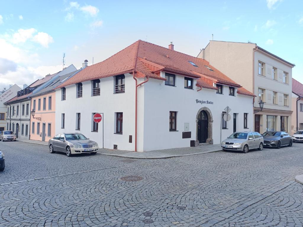 a street with cars parked in front of a white building at Penzion Kotva in Klatovy