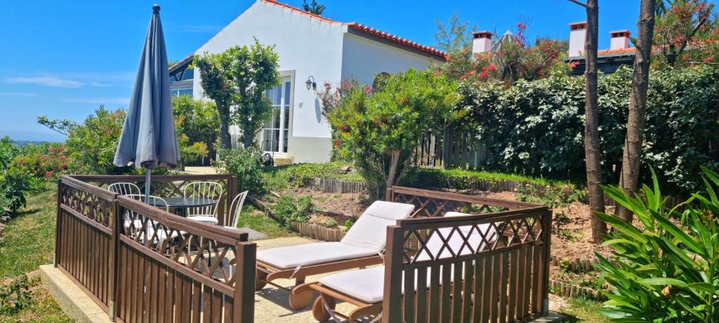 eine Terrasse mit 2 Stühlen und einem Sonnenschirm in der Unterkunft CASA PAVÃO (SALGADINHO - SELÃO DA EIRA) in São Teotónio