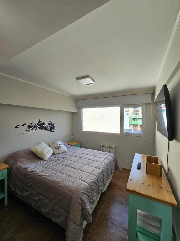 1 dormitorio con 1 cama, TV y mesa en Suite Vintage Bariloche en San Carlos de Bariloche