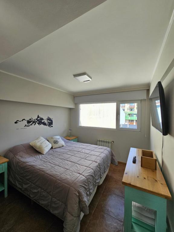 Un dormitorio con una cama, un televisor y una mesa. en Suite Vintage Bariloche, en San Carlos de Bariloche