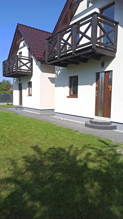 a white house with a balcony on top of it at Bałtyckie domki Kopalino in Kopalino
