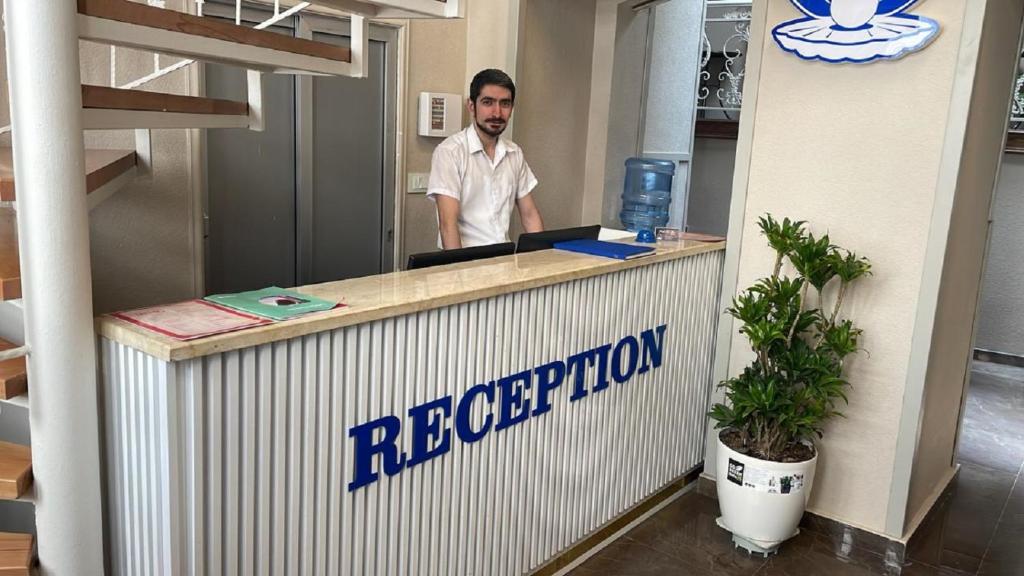 een man achter een receptie in een kantoor bij Perla De Mar Hotel in Baku