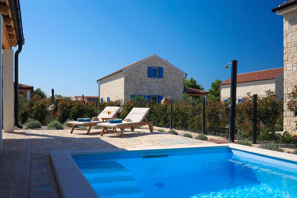 a swimming pool with two lounge chairs next to a house at Papa's Court V Pasman Villa with pool in Pašman