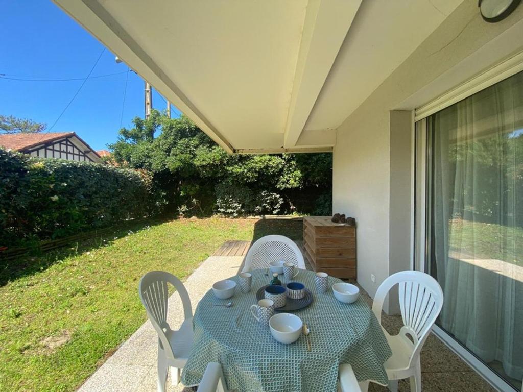 - une table bleue avec des chaises blanches sur la terrasse dans l'établissement Appartement cosy à Capbreton: Jardin, Terrasse, Parking, Wi-Fi, à 300m de la Plage - FR-1-413-133, à Capbreton