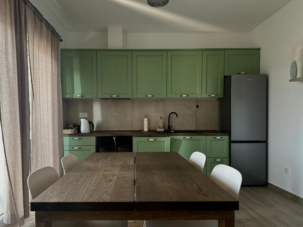 a kitchen with a wooden table and green cabinets at Apartment Giò in Tar