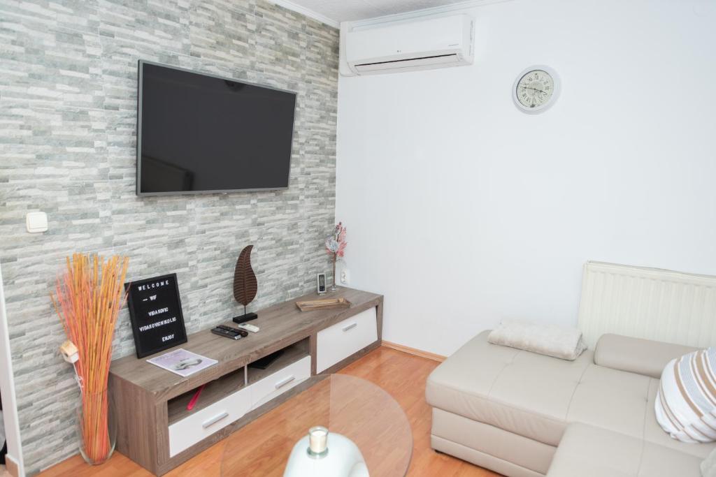 ein Wohnzimmer mit einem Sofa und einem TV an einer Backsteinwand in der Unterkunft Apartments Šentvid in Ljubljana