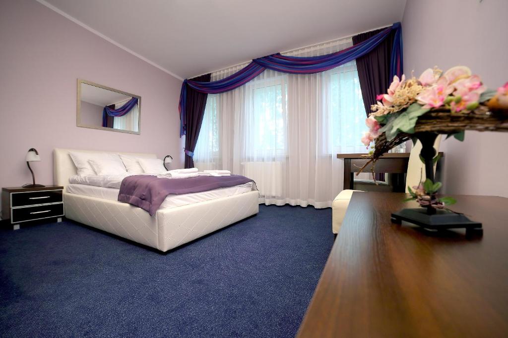 1 dormitorio con 1 cama y 1 mesa con flores en Zajazd Monki, en Mońki