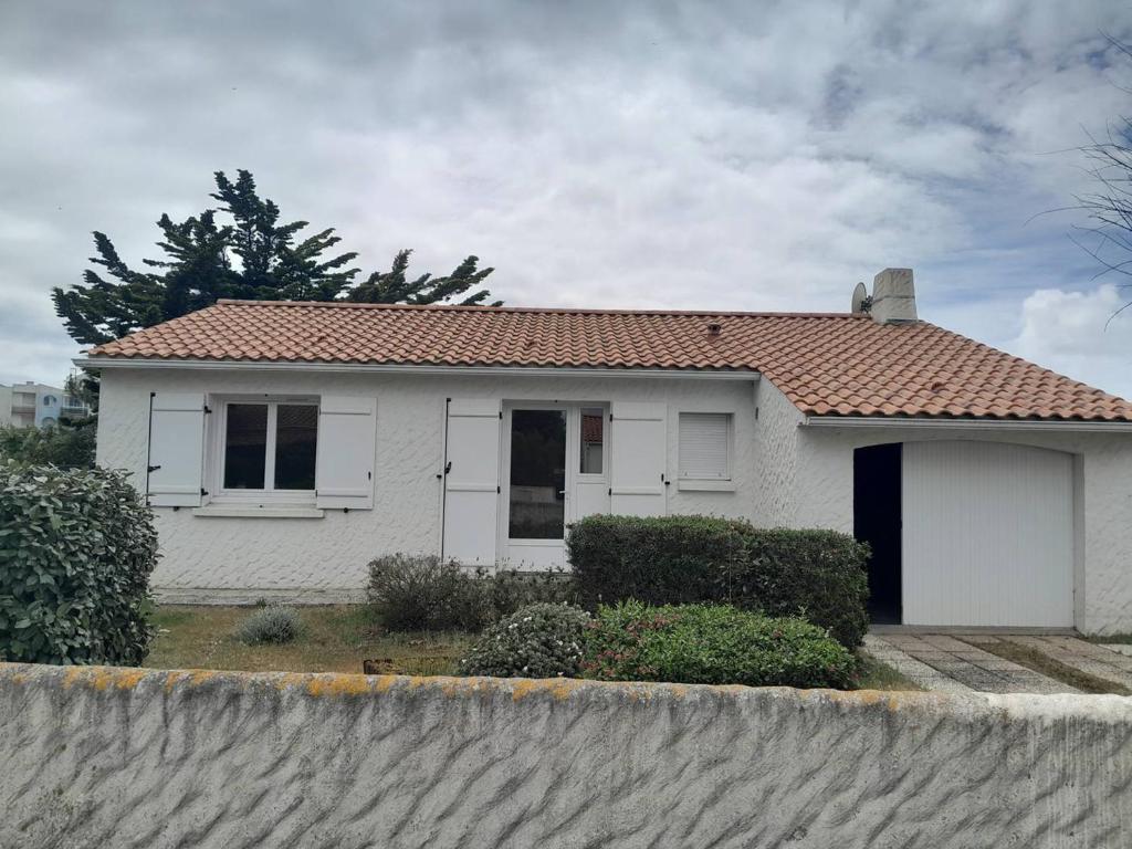une petite maison blanche avec un toit rouge dans l'établissement Villa T4 plain-pied proche plage, terrasse, parking, animaux acceptés - Saint-Gilles-Croix-de-Vie - FR-1-324-559, à Saint-Gilles-Croix-de-Vie