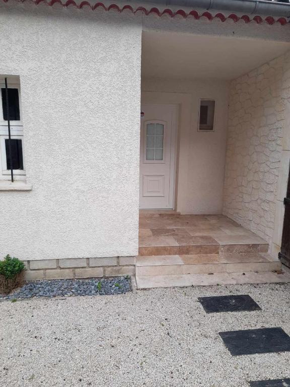 une maison blanche avec une porte blanche et une terrasse couverte dans l'établissement La bastide de Calés, à Lamanon