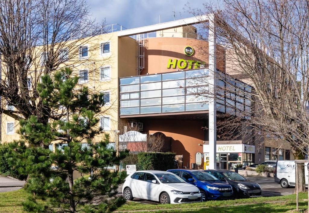 um hotel com carros estacionados em frente em B&B HOTEL Grenoble Centre Verlaine em Grenoble