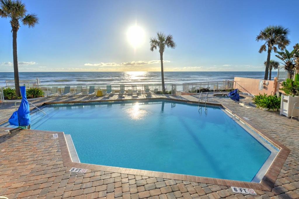 a large swimming pool with the ocean in the background at Bahama House - Daytona Beach Shores in Daytona Beach