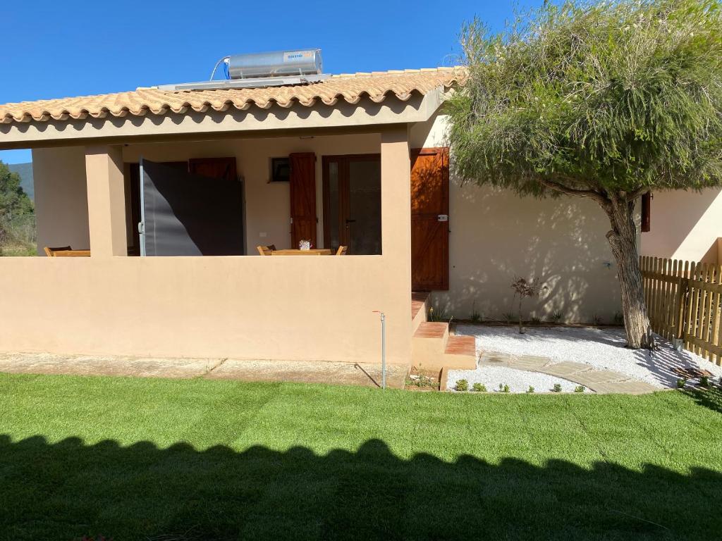 a house with a tree in front of a yard at La Collina: Il maestrale in Castiadas