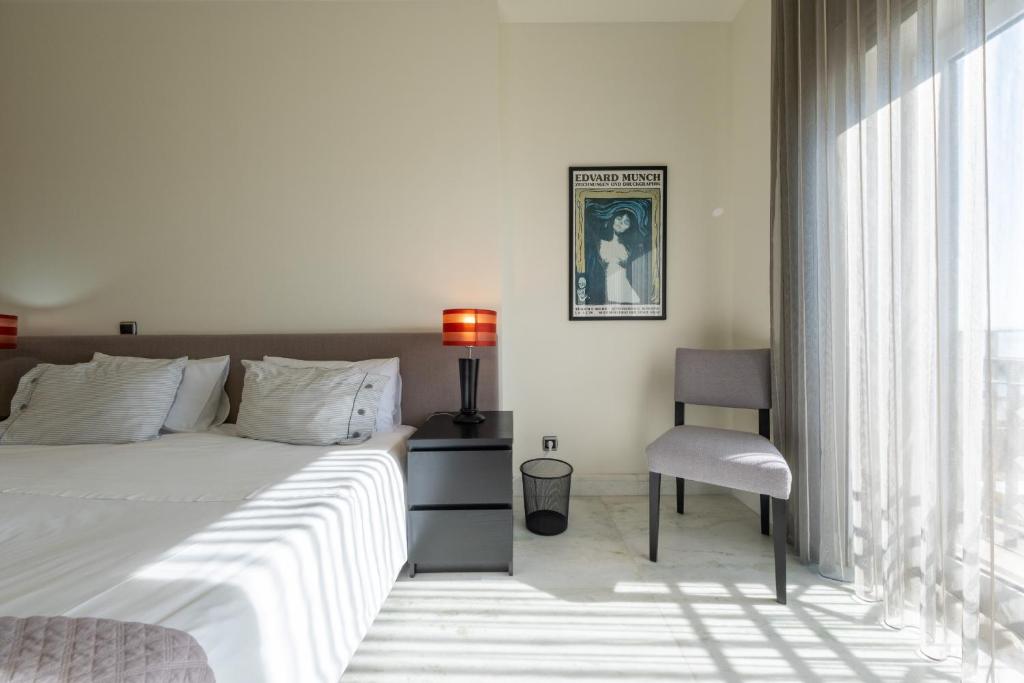 ein Schlafzimmer mit einem Bett, einem Stuhl und einem Fenster in der Unterkunft Fábrica da Ribeira 53 by Destination Algarve in Lagos