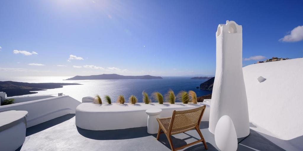 balcón con mesa y vistas al océano en Revelis Villa & Canava, en Fira