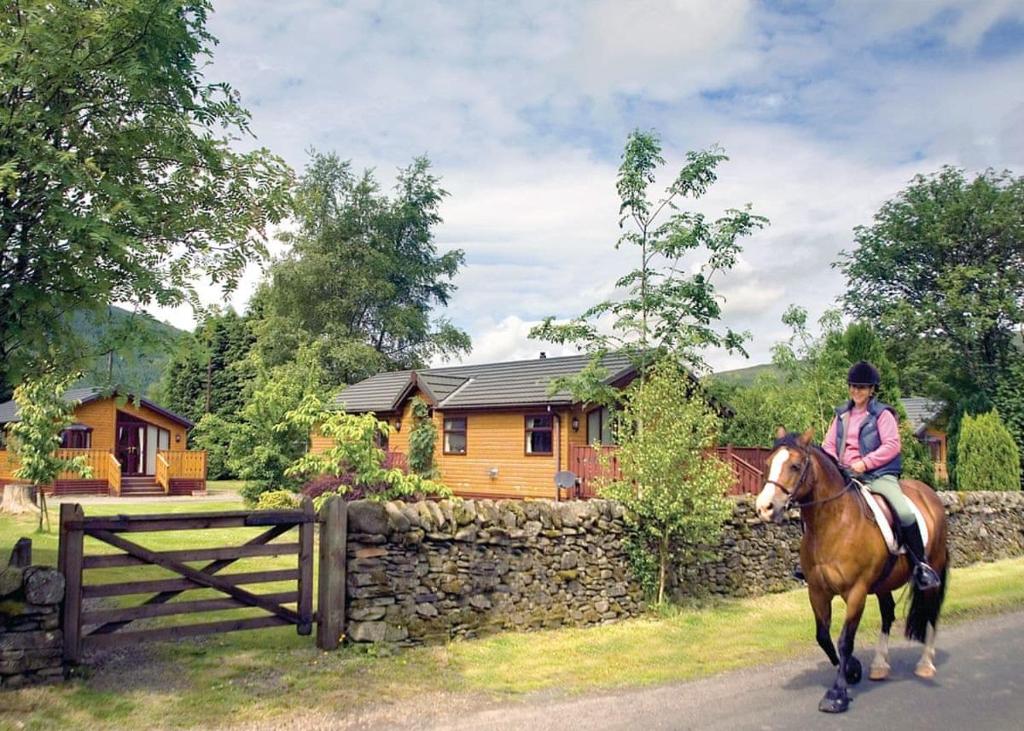 una mujer montando un caballo delante de una casa en Angecroft Park, en Ettrick
