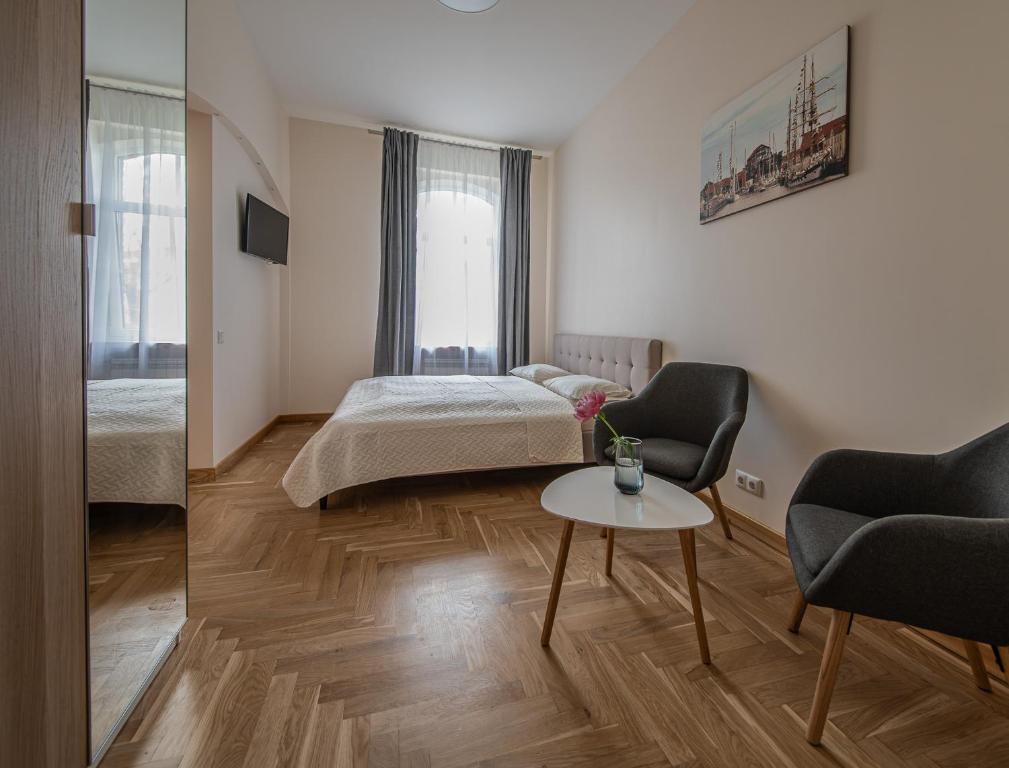 een slaapkamer met een bed, een tafel en stoelen bij Red Brick Apartments in Klaipėda